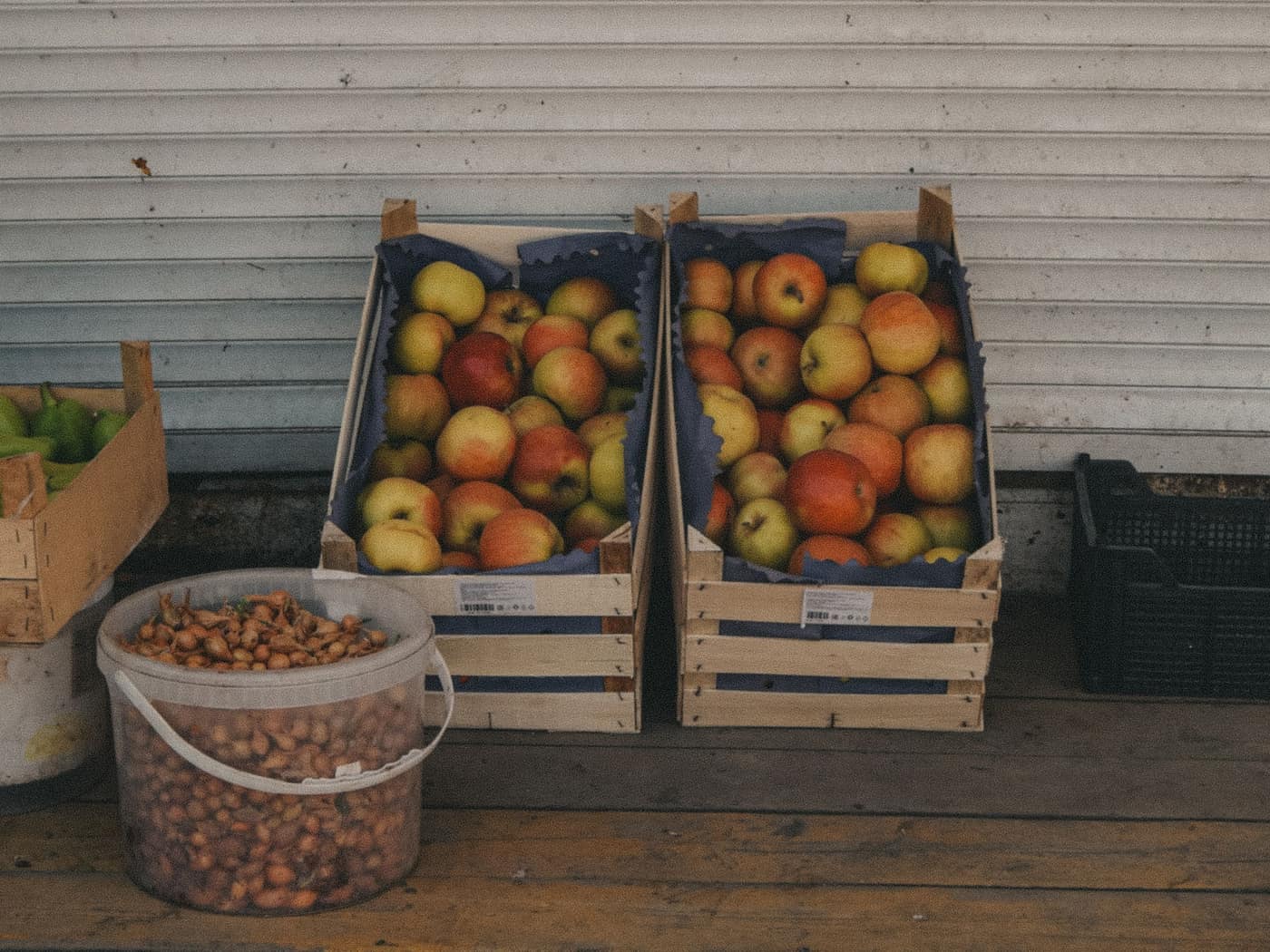 Wooden crates of apples and onions stacked on a market stall